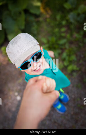 Carino piccolo ragazzo tenendo la sua mano padre Foto Stock