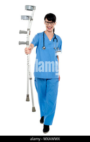 Giovani energica medico ortopedico camminando verso la telecamera con le stampelle in mano. Foto Stock