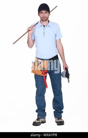 Plumber tenendo la lunghezza del tubo di rame e blow-torcia Foto Stock