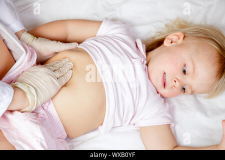 Pediatra esaminando bambina di addome mediante palpazione manuale Foto Stock