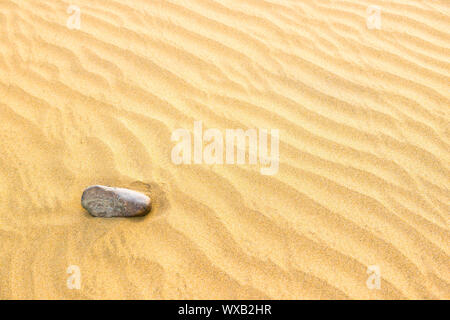 Pebble giacente sulla tessitura di giallo le dune di sabbia Foto Stock