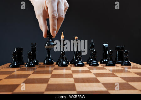 La mano si muove a scacchi pedina su di uno sfondo scuro Foto Stock