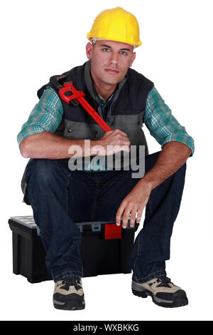 Artigiano seduta sul contenimento della casella degli strumenti chiave regolabile Foto Stock