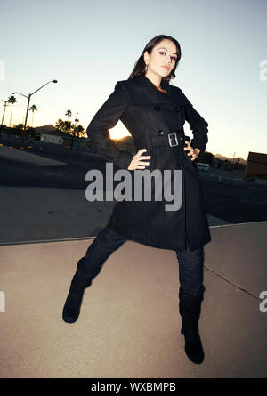 Bella donna iwearing trench nero al tramonto Foto Stock