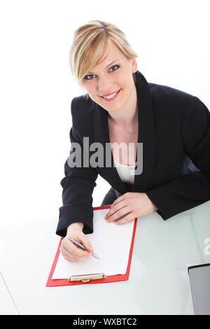 Angolo alto ritratto di un attraente giovane imprenditrice scrivendo su un foglio bianco di carta su un blocco appunti e sorridente fino alla telecamera isolata su whi Foto Stock