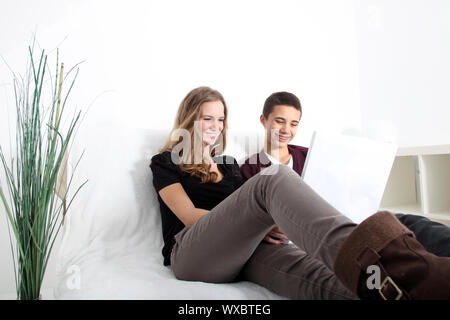 Basso angolo vista di due attraenti giovani studenti adolescente relax su un lettino a studiare insieme in un computer portatile Foto Stock