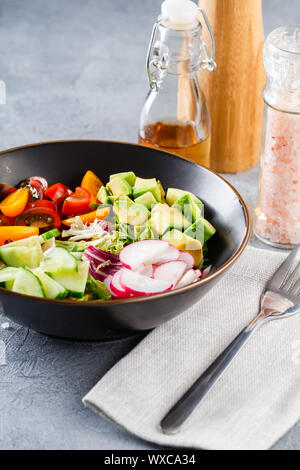 Vegano ciotola di buddha. Vegetariano sano con insalata di pomodori ciliegini, cetriolo, ravanello, avocado e lattuga. Foto Stock