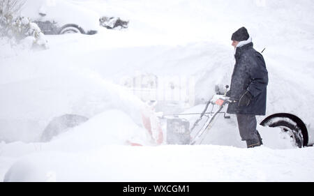 L'uomo soffiando la neve per ripulire il marciapiede e carraio Foto Stock