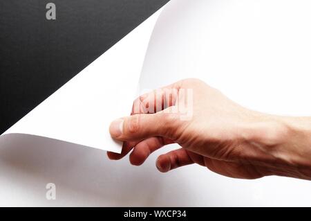 Mano girando sul foglio di carta bianco Foto Stock