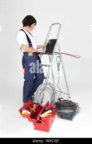 Elettricista femmina lavorando sul suo computer portatile Foto Stock