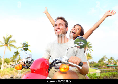 Happy free libertà matura la guida scooter eccitati su Vacanze estive Vacanze. Giovane coppia multietnica, donna asiatica, uomo caucasico Foto Stock