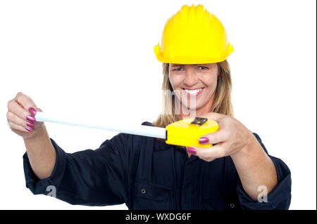 Felice costruzione Lavoratore che indossa il casco di sicurezza e tenendo premuto il nastro di misurazione. Foto Stock