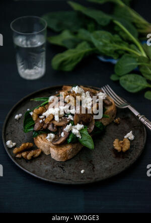 Moody cibo fotografia di funghi, feta e spinaci su pane tostato Foto Stock