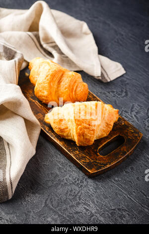 Croissant appena sfornati sul tagliere di legno, vista dall'alto Foto Stock