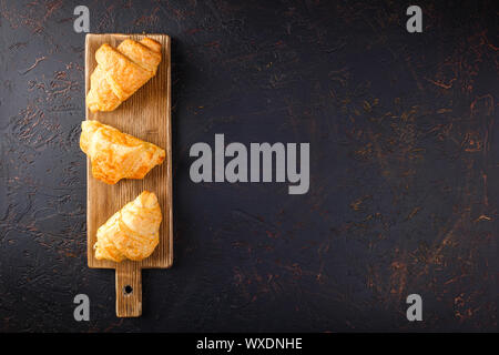 Croissant appena sfornati sul tagliere di legno, vista dall'alto Foto Stock