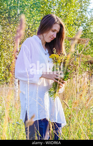 Ragazza raccoglie fiori selvatici ed erbe aromatiche Foto Stock