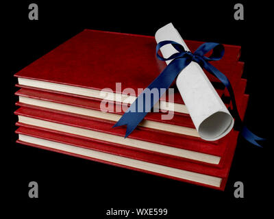 Un diploma con nastro blu su diversi libri. Isolato su nero. Foto Stock