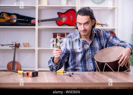 Giovane bello repairman riparazione di tamburo Foto Stock