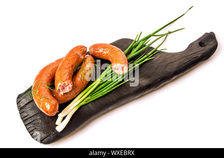 Salsicce alla griglia con cipolle su una scheda su uno sfondo luminoso. Succosa salsiccia anelli in una pila su uno sfondo bianco. Foto Stock