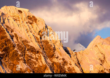 Bellissima la neve e il ghiaccio picchi di montagna al tramonto sotto un cielo espressiva Foto Stock