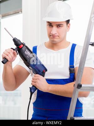 Repairman lavora con il trapano elettrico in officina Foto Stock