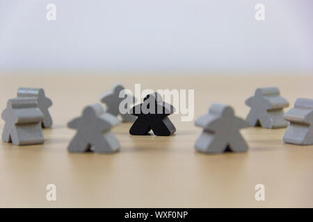 Grigio pezzi di gioco e un nero meeple, il concetto di diversità Foto Stock