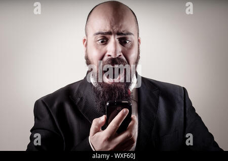 Divertente ed elegante uomo barbuto urlando al telefono su sfondo la vignettatura Foto Stock