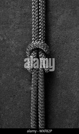 Piegare nodo sul cavo nero in tessuto nero lo sfondo Foto Stock