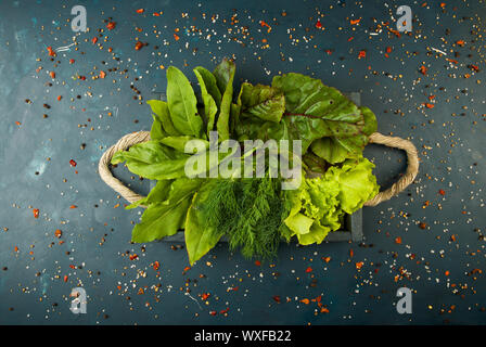 Ortaggi freschi su una scatola di legno su una pietra scura sullo sfondo. Il concetto di vintage. GREEN SORREL LASCIA Foto Stock