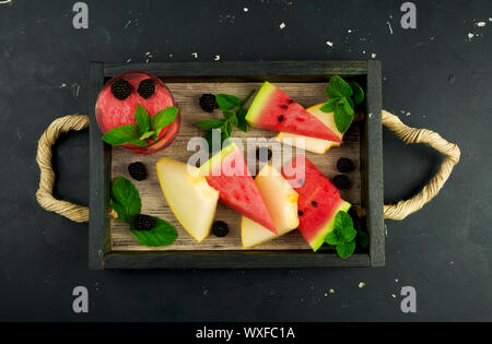 Cocomero melone more di menta e un bicchiere di succo di frutta in scatola in background. Mature cocomero melone succosa con BLACKBERR Foto Stock