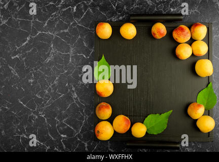 Albicocche mature giacente sul Tray nero su sfondo scuro Foto Stock