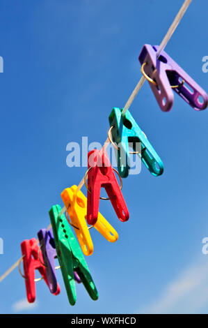 Abbigliamento colorato pioli sulla linea contro il cielo blu Foto Stock