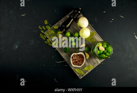 Verdure pomodori e spezie sulla scheda. Cipolle Aglio pomodori spezie aneto grigio sul pannello di legno su un rilievo di superficie in pietra. Foto Stock