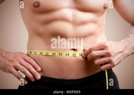 Montare l'uomo misurando la sua vita dopo un allenamento nella palestra Foto Stock