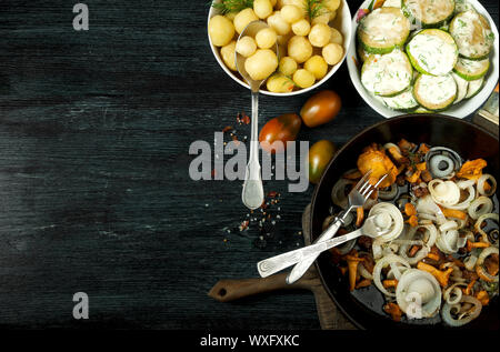 Verdure sullo sfondo. Zucchine fritte salsa in una piastra. Giovani patate bollite con aneto in una ciotola. Fried chanterelle poltiglia Foto Stock