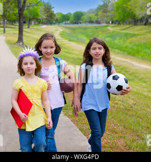 Bambini Bambino le ragazze a piedi schoool con sport palle di cartelle e zaini in parco all'aperto Foto Stock