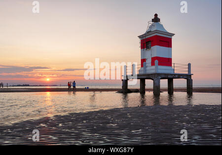 Faro al tramonto in Italia con la spiaggia Foto Stock