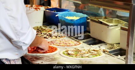 Diverse pizze essendo realizzati in una cucina Foto Stock