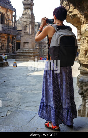 La ragazza riprese turistiche una foto su uno smartphone mentre si cammina in un tempio complesso. Kailash tempio di Ellora.India Foto Stock