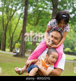 Sud-est asiatico famiglia divertendosi al verde parco all'aperto. Bella famiglia musulmana che suonano insieme. Foto Stock