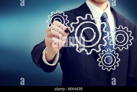 Imprenditore con ingranaggi - concetti di lavoro di squadra, efficienza, parti a incastro. Foto Stock