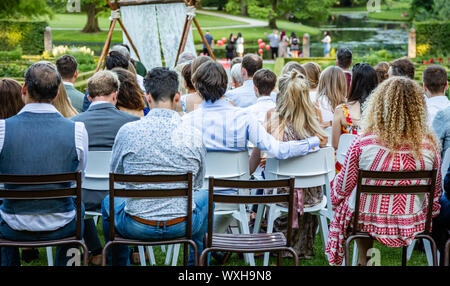 Rotterdam, Paesi Bassi. Giugno 29, 2019. Ijsvrij festival in un parco. Le persone sono seduti, in attesa di una cerimonia che si avvia. Vista posteriore, blur natura indietro Foto Stock