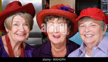 Tre simpatici senior donne che indossano il cappello rosso Foto Stock