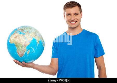 Attraente casual giovane azienda globo nel suo canto isolato su bianco Foto Stock
