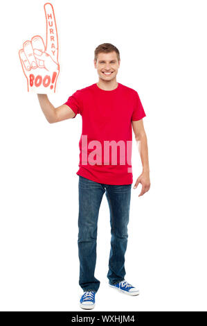 Casual guy mostrando grande appuntito di boo hurray mano giocattolo. A piena lunghezza ritratto Foto Stock