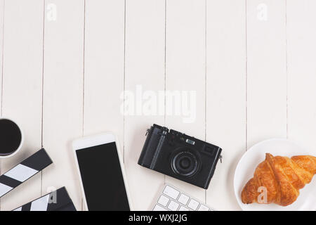 Segno di pellicola con lo smartphone, fotocamera, torta, tastiera su uno sfondo di legno Foto Stock