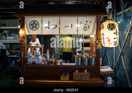 Taichung, Taiwan: piccolo, tradizionale giapponese del cibo di strada in stallo il mercato notturno con una lanterna giapponese Foto Stock