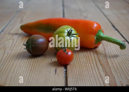 Insieme multicolore lungo i peperoni e pomodori cimelio di famiglia su una tavola in legno rustico Foto Stock