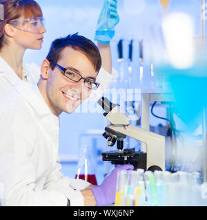 Ritratto di un giovane ricercatore maschio microscopia in scienze della vita (forensics, microbiologia, Biochimica, Genetica, oncologia...)laboratorio. Femmina Foto Stock