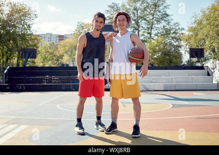 A tutta lunghezza foto di due atleti con basket sul parco giochi sul giorno di estate Foto Stock